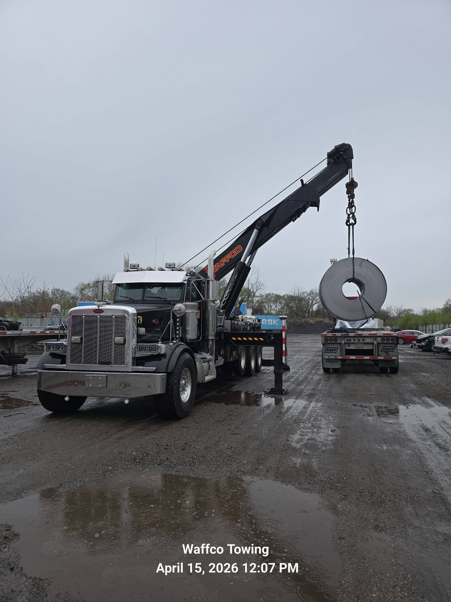 Waffco rotator lifting a steel coil from a flatbed trailer