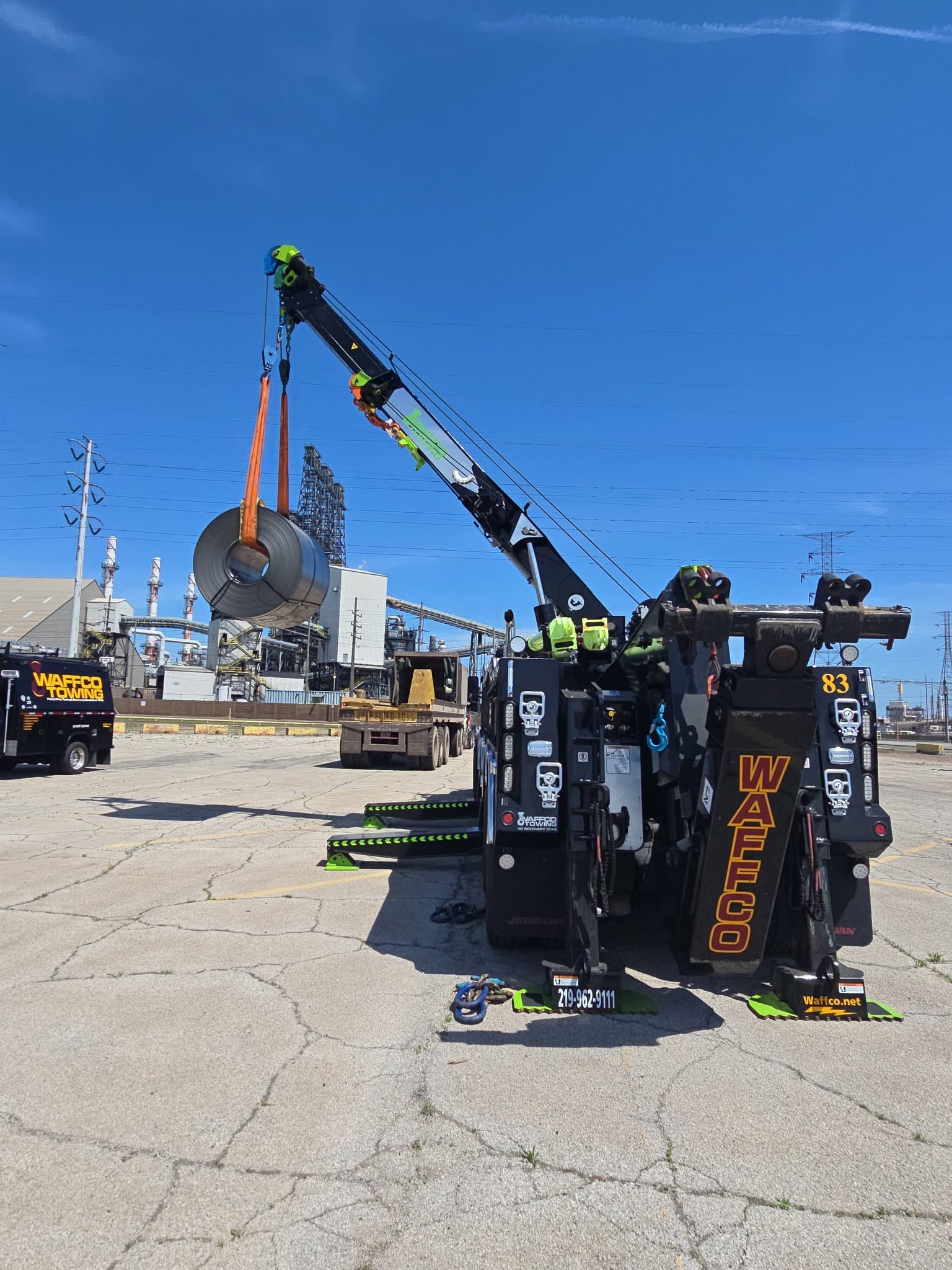 Waffco rotator lifting a steel coil near an industrial mill